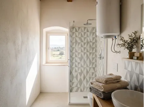 Bagno della Camera Mirto: doccia con piastrelle a motivi geometrici, scaldabagno e finestra sulla campagna